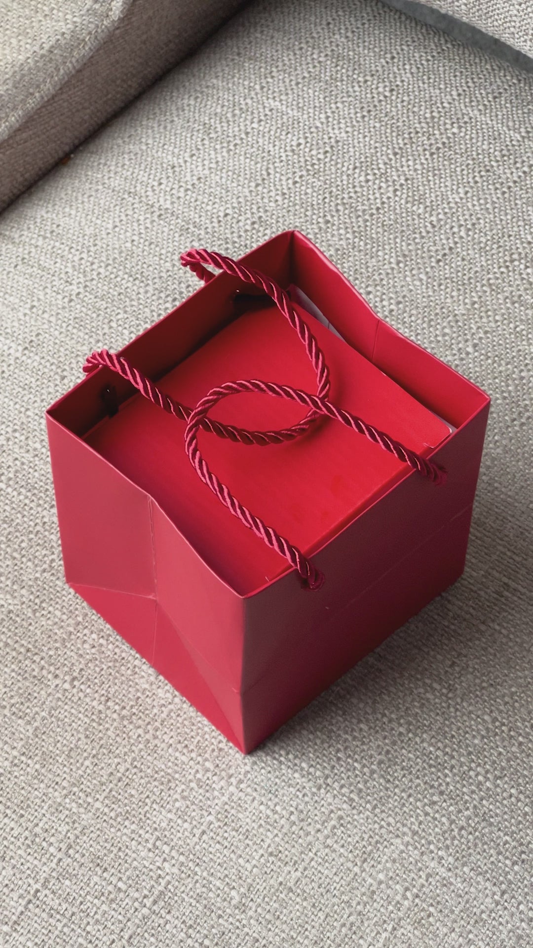 red rose on top of rotating box with gold loveknot necklace